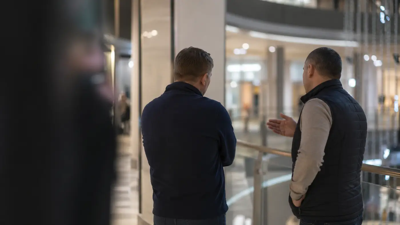 Dvaja muži v nákupnom centre počas rozhovoru, ktorý sa stal podnetom k úvahe o dostupnosti dôstojného úsmevu.